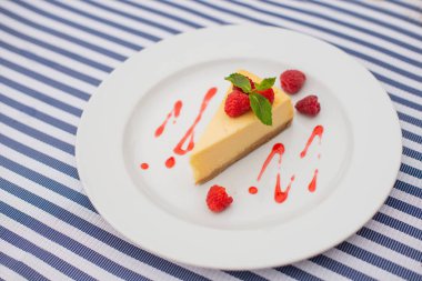 Lokantada içinde nane yaprağı olan ahududu olan bir tabakta tatlı peynirli kek.