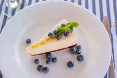 Bir tabak yaban mersinli tatlı cheesecake. Nane yaprağıyla bir restoranda.