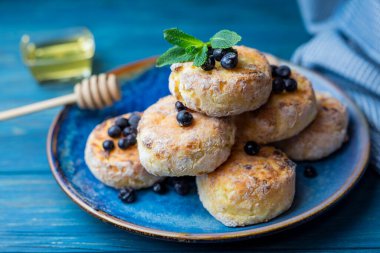 cheese pancake with cottage cheese blueberries on a blue plate for breakfast with honey and blueberries