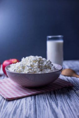 Süt ürünü süzme peynir bir tabak süt ve elma ile ahşap bir arka planda.