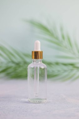 Cam şişede kozmetik ürünler ve arka planda cilt bakımı için pipet var.