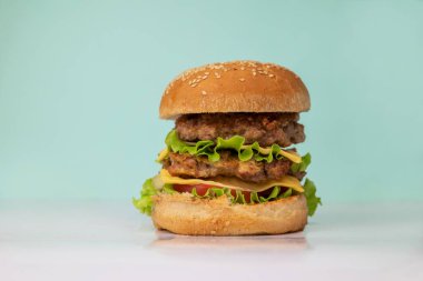 Sebzeli hamburger. Turkuaz arka planda et pirzolası.