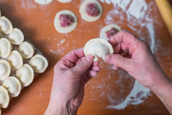 stock image an elderly man cook makes sculpts dumplings from dough and minced meat