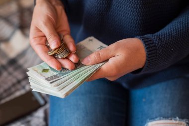 Kız elinde para tutuyor. Zloty 'leri ve bozuk paraları parlatıyor. Ödeme için de maaşını.