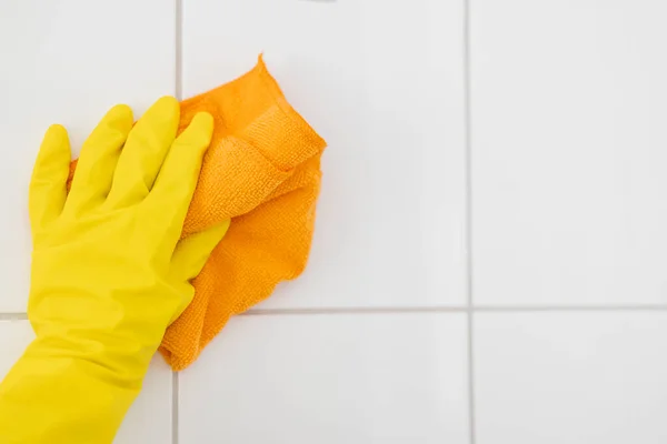 girl in rubber gloves with a rag cleans the bathroom