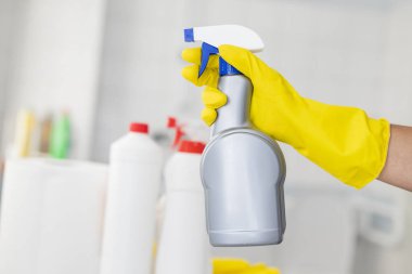 Lastik eldivenli kız otel çalışanı temizlik ürünleriyle banyoyu temizliyor. Temizlik ve dezenfeksiyon araçlarıyla.