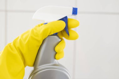 Lastik eldivenli kız otel çalışanı temizlik ürünleriyle banyoyu temizliyor. Temizlik ve dezenfeksiyon araçlarıyla.