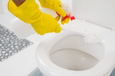 a girl in gloves cleans the ceramic toilet with a brush and disinfectant and cleanliness