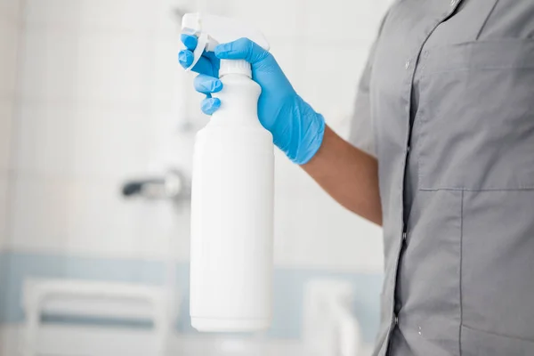 girl hotel worker in rubber gloves with cleaning products does cleaning in the bathroom with a means for cleanliness and disinfection