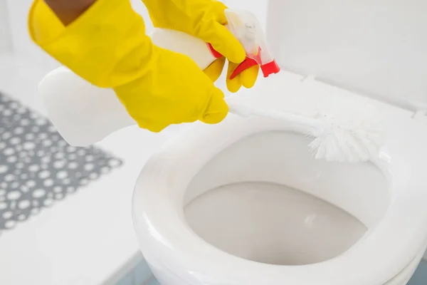 a girl in gloves cleans the ceramic toilet with a brush and disinfectant and cleanliness