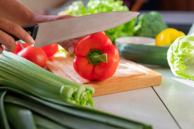 Mutfakta aşçı kız kırmızı biber ve sebze kesiyor.