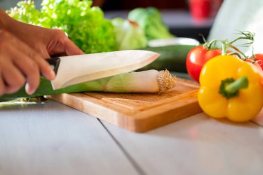 Kız aşçı mutfakta kereviz doğruyor tahta bir tahtada bıçakla sebze kesiyor.