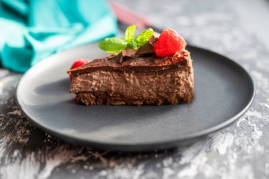 delicious sweet chocolate cheesecake cake in a restaurant with raspberries and mint leaf on a plate