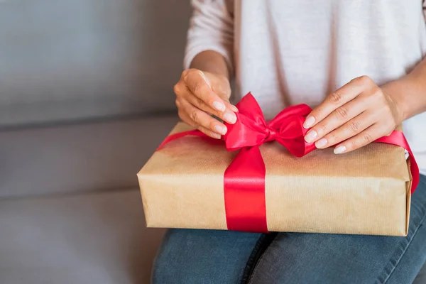 girl unties the bow of a surprise gift box for the holiday