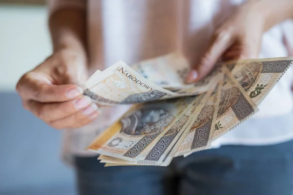 Kız elinde para tutuyor. Zloty 'leri ve bozuk paraları parlatıyor. Ödeme için de maaşını.