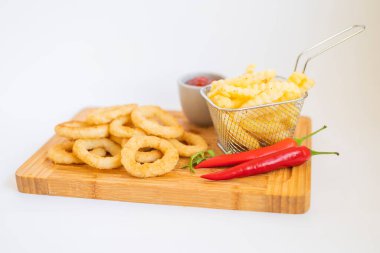 Fast food kızarmış soğan halkaları kızarmış patates kızartması ve ahşap bir tahtanın üstünde sos.