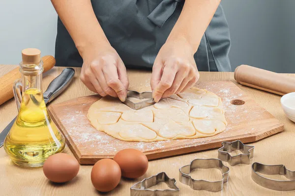 Woman Gray Apron Cuts Out Heart Shaped Cookies Dough Her — Stock Photo, Image