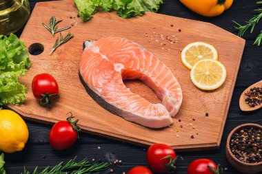 Koyu bir arka planda, limonlu, domatesli, biberiyeli, biberli, baharatlı ve marullu somon bifteği. Sağlıklılık. Yukarıdan görüntüle.