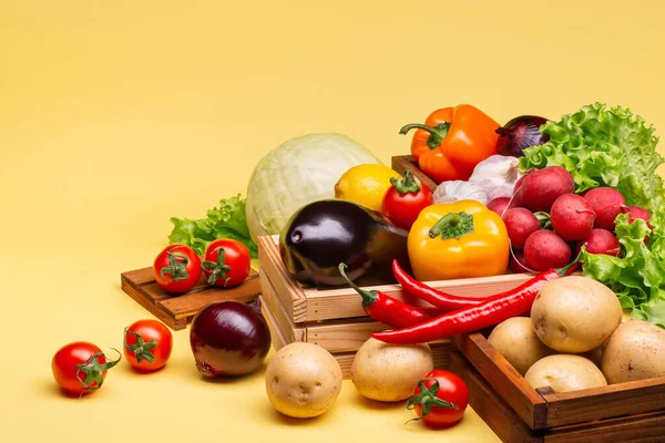 Sağlıklı beslenmek için çeşitli taze ve sağlıklı sebzeler. Sağlıklılık. Domates, marul, turp, patlıcan, patates, biber, lahana, sarımsak, ahşap kutularda limon. Yan görüş. Boşluğu kopyala.