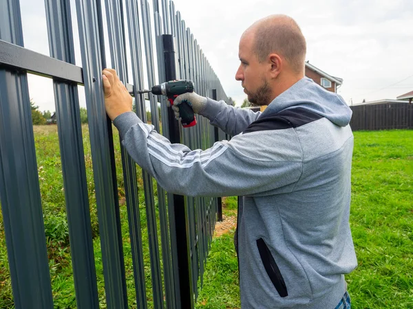 Hombre Que Usa Destornillador Tuerce Una Cerca Metálica Cerca Trabajador — Foto de Stock