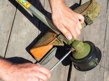 Özel bir anahtarla çim biçmek için makina vites kutusundaki vidayı sökmeye yakın plan. Ekipman bakımı, üst görünüm