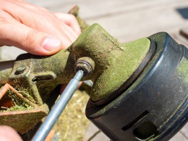 Özel bir anahtarla çim biçmek için makina vites kutusundaki vidayı sökmeye yakın plan. Ekipman bakımı