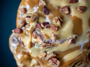 Karamel soslu ve cevizli tarçınlı çörekler. Siyah tabak, tabağın bir parçası, seçici odaklanma. Üst manzara, düz uzanma