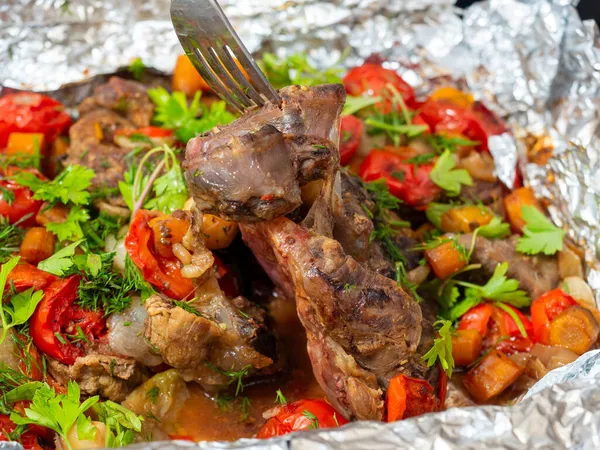 Sebzelerle fırında pişirilmiş ve taze otlarla süslenmiş lezzetli dana eti yakın plan. Yemek arkaplanı. Lezzetli ve sağlıklı bir yemek.