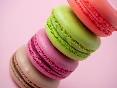 Farklı renklerde geleneksel badem kurabiyeleri pembe arka planda bir piramidin içinde dururlar. İzole edilmiş ürün, tatlılar, şekerlemeler.