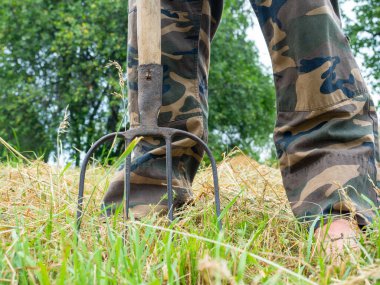 Adamın ayağının yanındaki köy villaları. Ayaklarının altındaki saman. Tarım kavramı. Güneşli yaz günü, çıplak ayakla