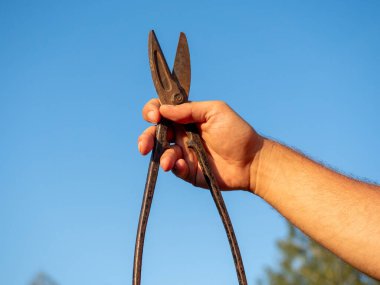 Paslı metal bir makası tutan bir adamın yakın çekimi. Bulanık arkaplan