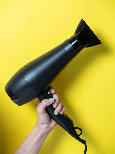 Asciugacapelli Nero Nella Mano Una Donna Uno Sfondo Giallo Prodotti — Foto Stock