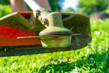 Metal bıçak şeklinde bir başlığı olan bir çim biçme makinesinin yakın çekimi. Site bakımı, çim biçme