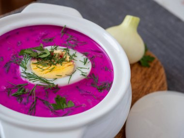 Ahşap bir tahtanın üzerinde soğuk chlodnik çorbası. Yarım yumurtayla süslenmiş, pancar kökü ve kefirden yapılmış Polonya usulü Belarus ve Rus mutfağı çorbası. Sağlıklı yemek.