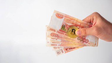 Bir adamın eli Rus banknotlarını ve Bitcoin 'i tutuyor. Madencilik ve kazanç kavramı. Boşluğu kopyala