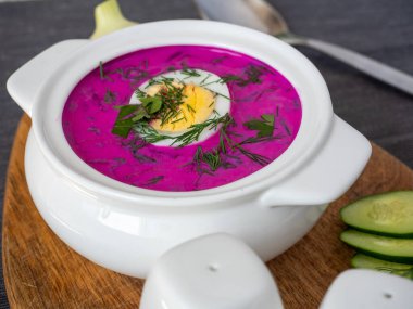 Ahşap bir tahtanın üzerinde soğuk chlodnik çorbası. Yarım yumurtayla süslenmiş, pancar kökü ve kefirden yapılmış Polonya usulü Belarus ve Rus mutfağı çorbası. Sağlıklı yemek.