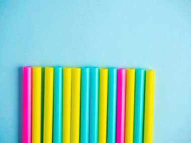 Mavi kağıt arka planda çok renkli plastik tüplerin yakın çekimi. Üst manzara, düz uzanma