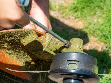 Özel bir anahtarla çim biçmek için makina vites kutusundaki vidayı sökmeye yakın plan. Ekipman bakımı