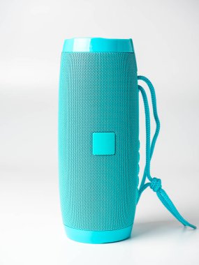 Beyaz arka planda duran mavi bir kablosuz müzik hoparlörünün yakın çekimi. Ön manzara. Stüdyo çekimi