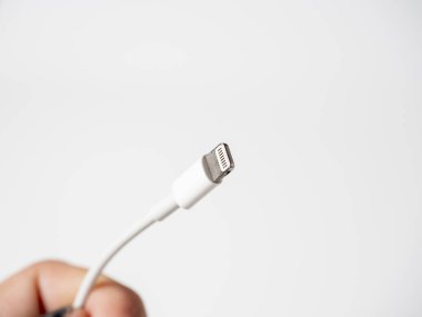 Beyaz arka planda izole edilmiş beyaz bir yıldırım kablosunun yakın çekimi. Cihazları şarj etmek ve bilgi göndermek için kablo