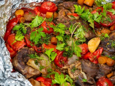 Sebzelerle fırında pişirilmiş ve taze otlarla süslenmiş lezzetli dana eti yakın plan. Yemek arkaplanı. Lezzetli ve sağlıklı bir yemek.