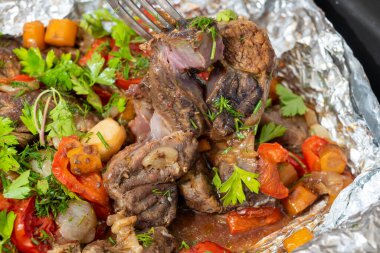 Sebzelerle fırında pişirilmiş ve taze otlarla süslenmiş lezzetli dana eti yakın plan. Yemek arkaplanı. Lezzetli ve sağlıklı bir yemek.