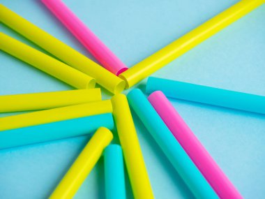 Çok renkli plastik borular mavi kağıt arka planda serilmiştir. Üst manzara, düz uzanma