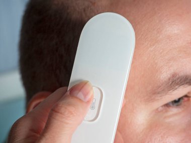 Elektronik termometre tabancası kullanarak insan sıcaklığının yakın çekim ölçümü. Hastalık, salgın, sağlık kontrolü kavramı.