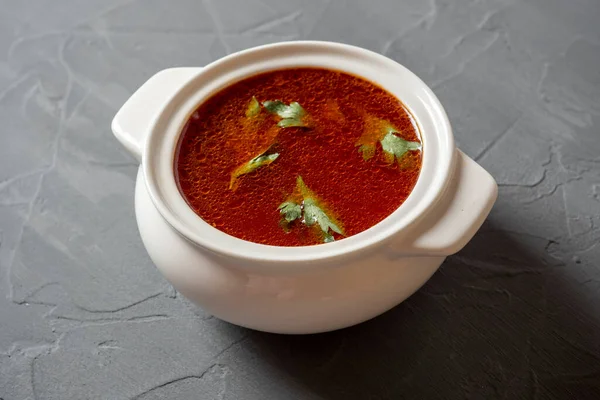 灰色の質感の背景に白いセラミックスープボウルにスープのボルシチのクローズアップ ロシアとウクライナの伝統的なスープ スープの上に緑が浮かんでいます サイドビュー — ストック写真