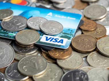 03.01.2022 Rusya, Moskova. Sberbank ve Sberbank banka kartlarının yakın çekimleri madeni paraların arka planında yatıyor. E-ticaret, bankacılık, finans kavramı. Mastercard, Visa