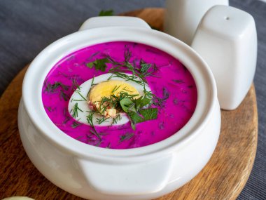 Ahşap bir tahtanın üzerinde soğuk chlodnik çorbası. Yarım yumurtayla süslenmiş, pancar kökü ve kefirden yapılmış Polonya usulü Belarus ve Rus mutfağı çorbası. Sağlıklı yemek.