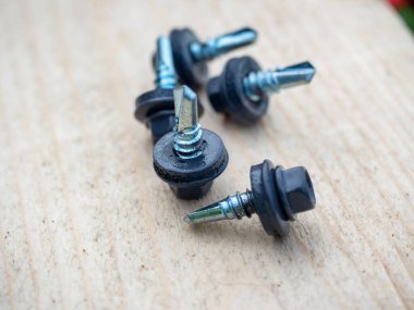 Bir grup çatı vidası ahşap arka planda griye boyanmış..