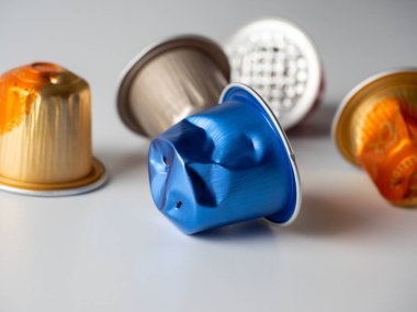 Beyaz arka planda bir sürü renkli alüminyum kahve kapsülü bulunur. Paketlemeyi yeniden kullanma kavramı. Ekoloji, doğayla ilgilenme. Atık geri dönüşümü