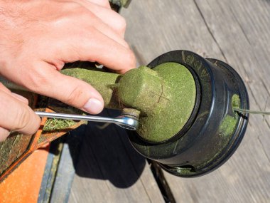 İngiliz anahtarıyla benzin makinanın vidasının vidasını sökmeye yakın plan. Ekipmanların bakımı. Üst görünüm